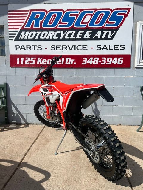 Red dirt bike parked outside Roscos Motorcycle & ATV shop sign