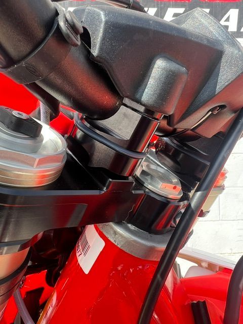 Close-up of a red motorcycle frame, engine, and handlebars in a garage or workshop.