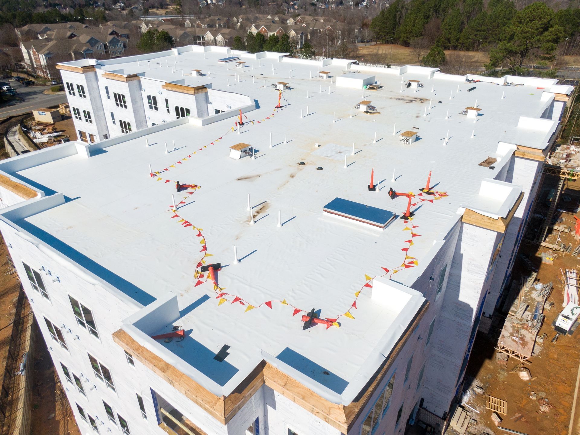 Aerial view of a white rooftop with colorful pennant flags and a skylight on a building under construction