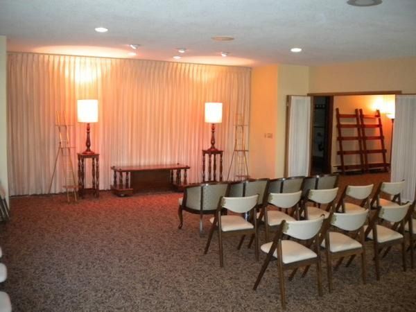 Small stage with curtains and lamps, rows of folding chairs set up in a banquet or meeting room.