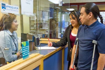 Customer service desk with two people speaking to a clerk behind glass at a counter