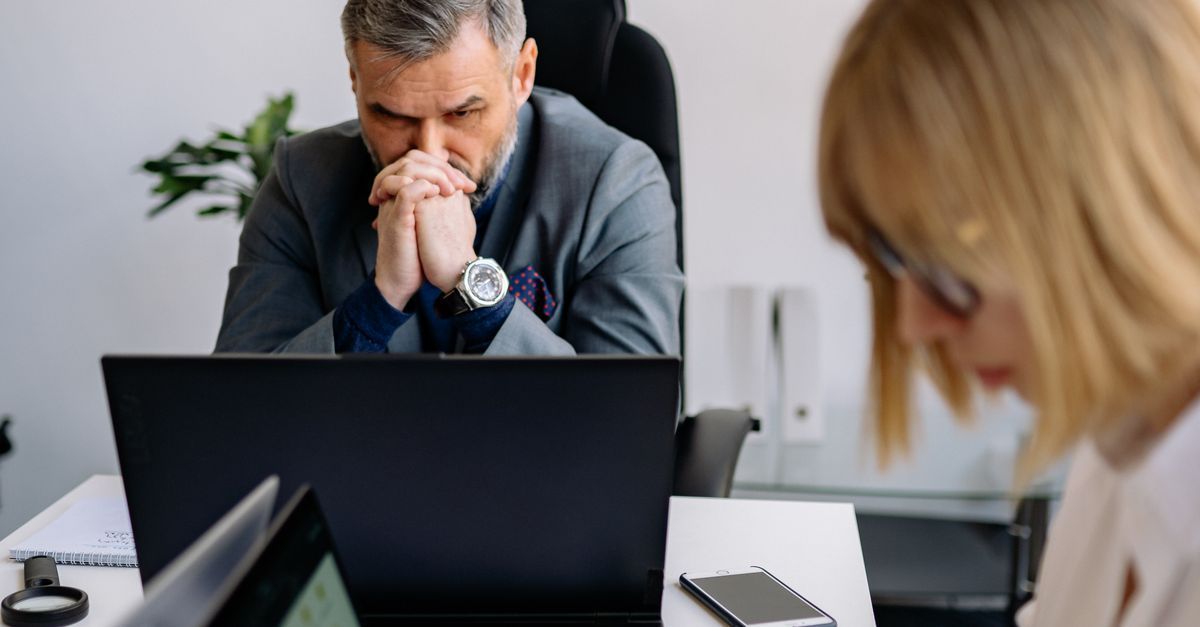 Gestor de TI em escritório corporativo revisando permissões de acesso dos usuários no notebook