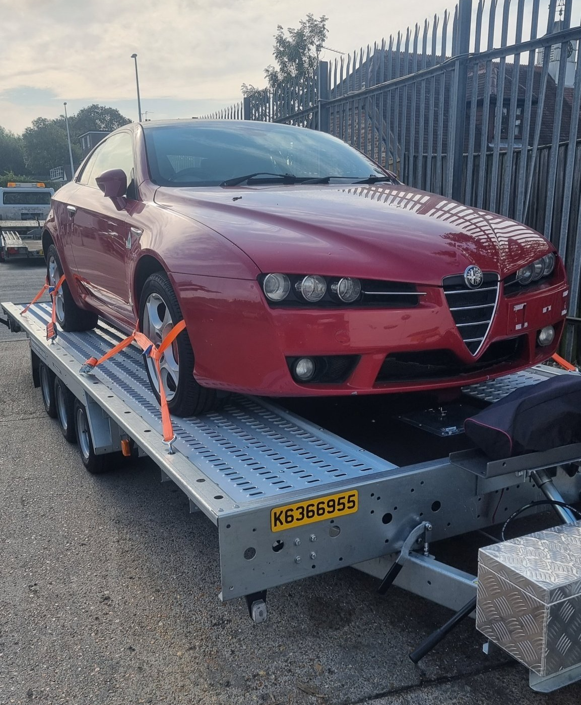A red Alfa Romeo on a trailer towed by a Mercedes Sprinter, ready for transport by MTC Transport