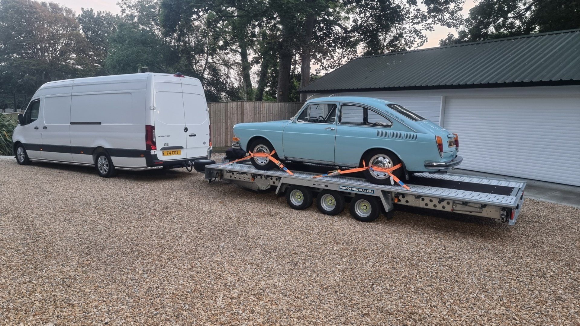 A light blue classic car on a trailer towed by a Mercedes Sprinter, ready for transport by MTC Transport