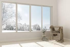 An empty room with a chair and a plant in front of a large window.