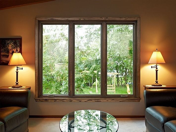 A living room with three windows and a glass coffee table
