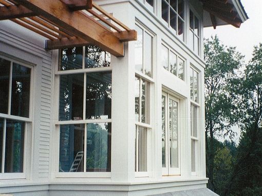 A white house with lots of windows and a wooden pergola