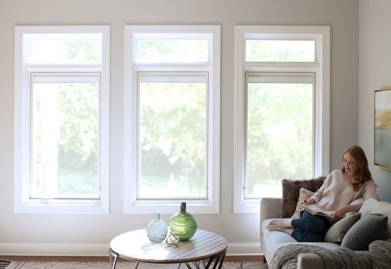 A woman is sitting on a couch in a living room reading a book.