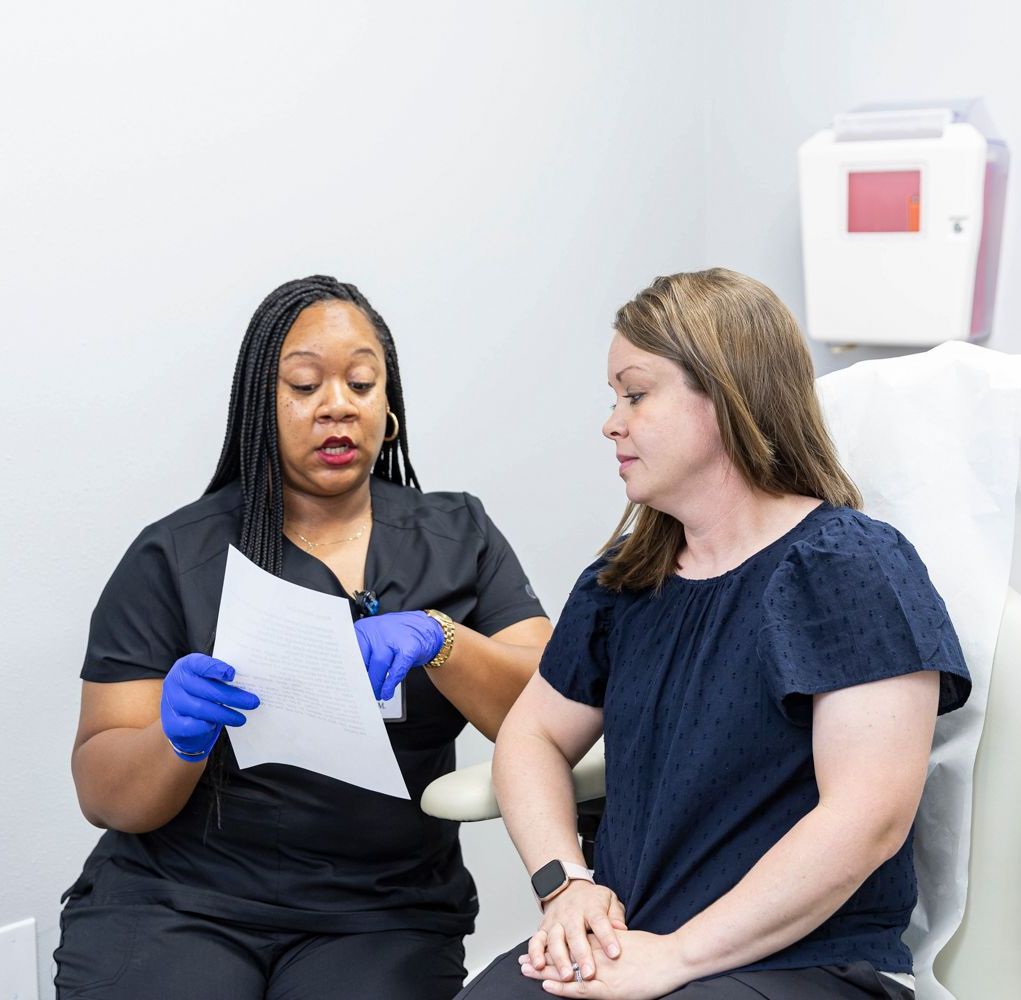 A nurse is talking to a patient while holding a piece of paper at Summit Dermatology in Pensacola, Florida