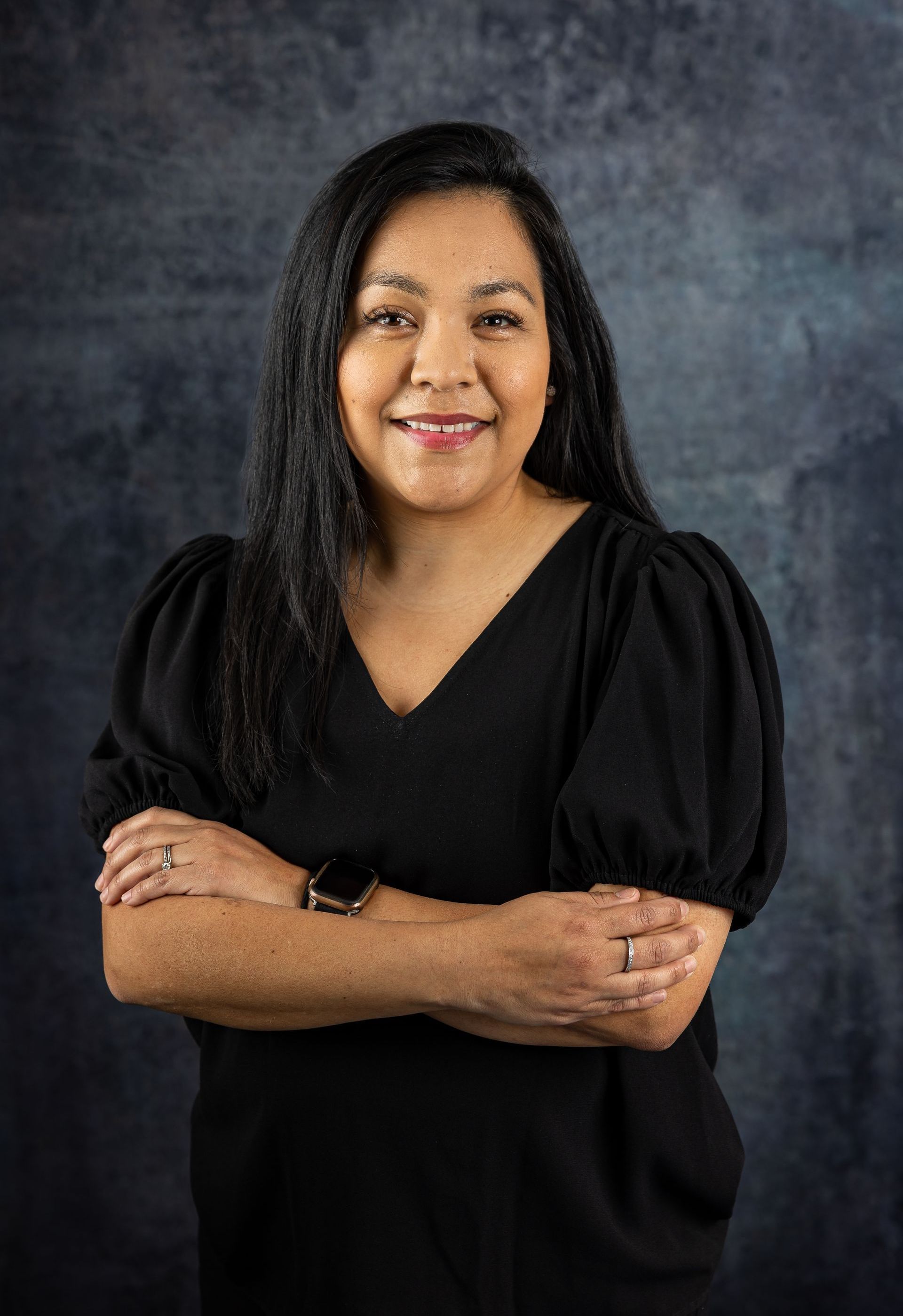 A woman in a black shirt is posing for a picture with her arms crossed.