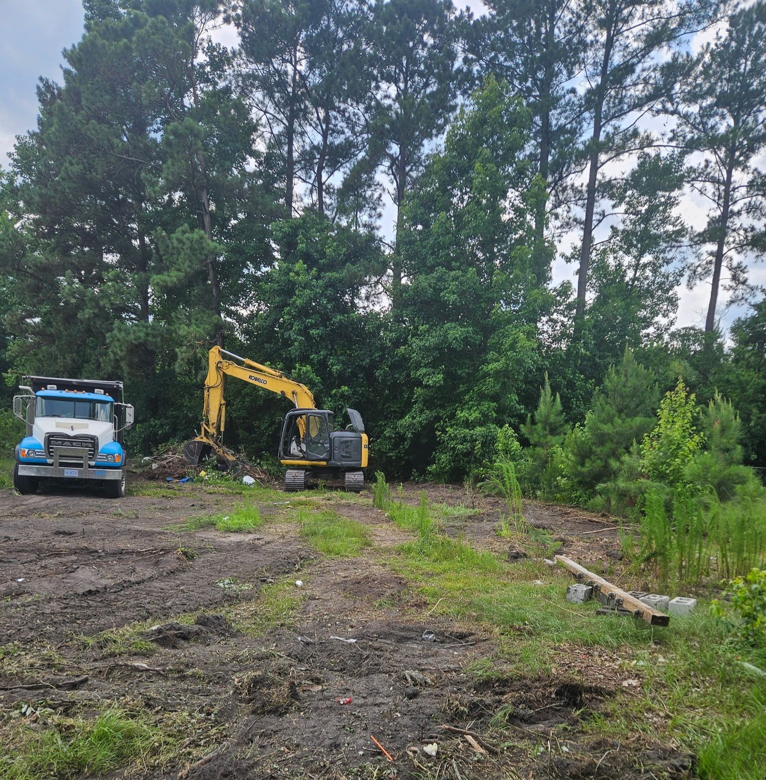 Excavator loading debris into a black dump truck at a muddy construction site under a blue sky. Excavator loading debris into a black dump truck at a muddy construction site under a blue sky.