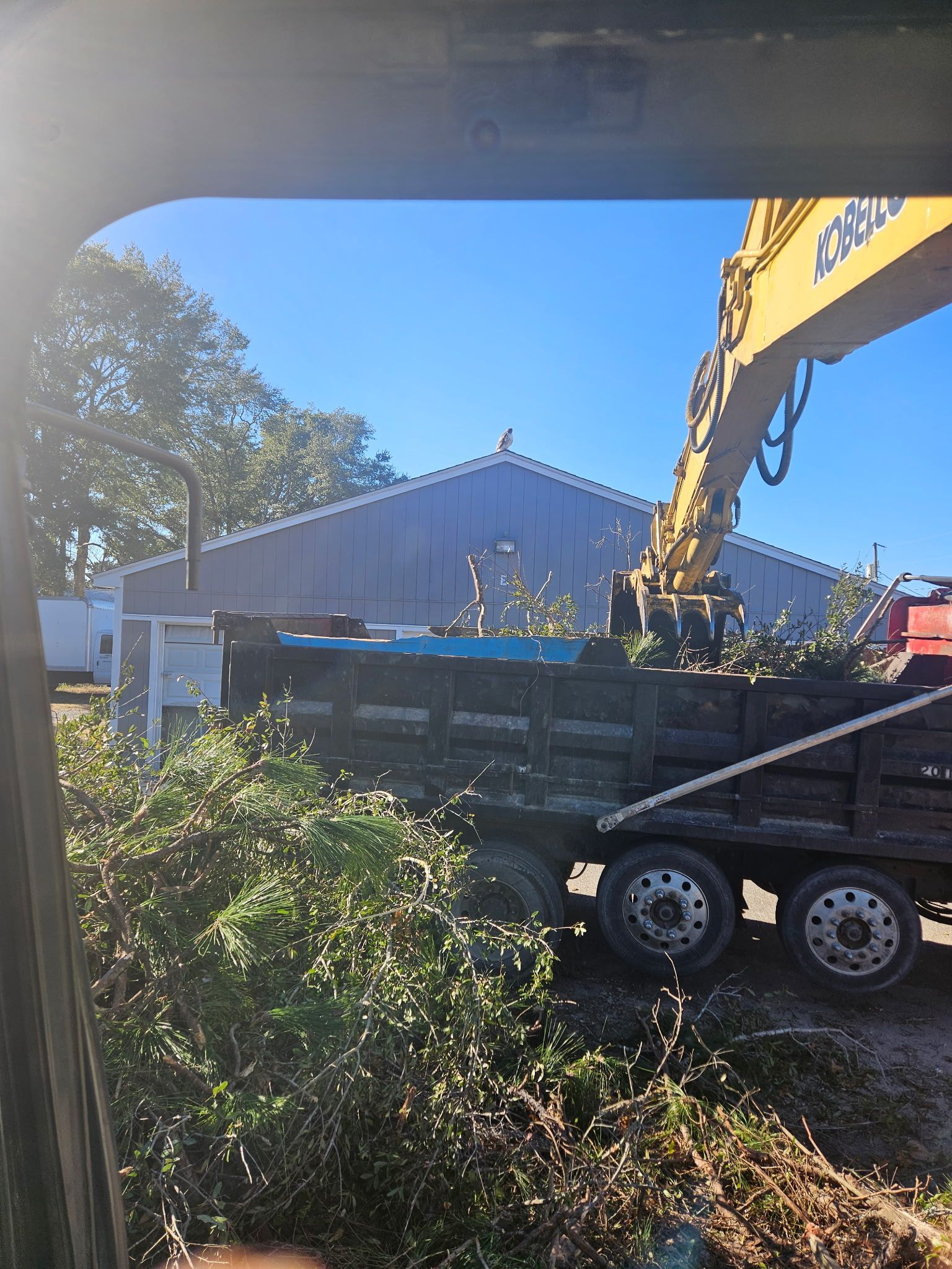 Excavator loading dirt into a dump truck at a muddy construction site, with another machine nearby. Excavator loading dirt into a dump truck at a muddy construction site, with another machine nearby.