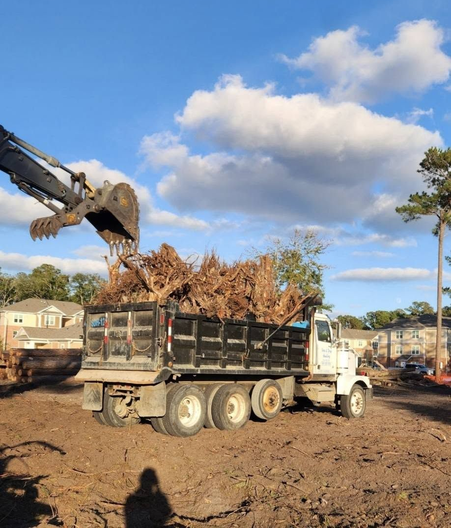Excavator loading debris into a dump truck at a construction site under a blue sky