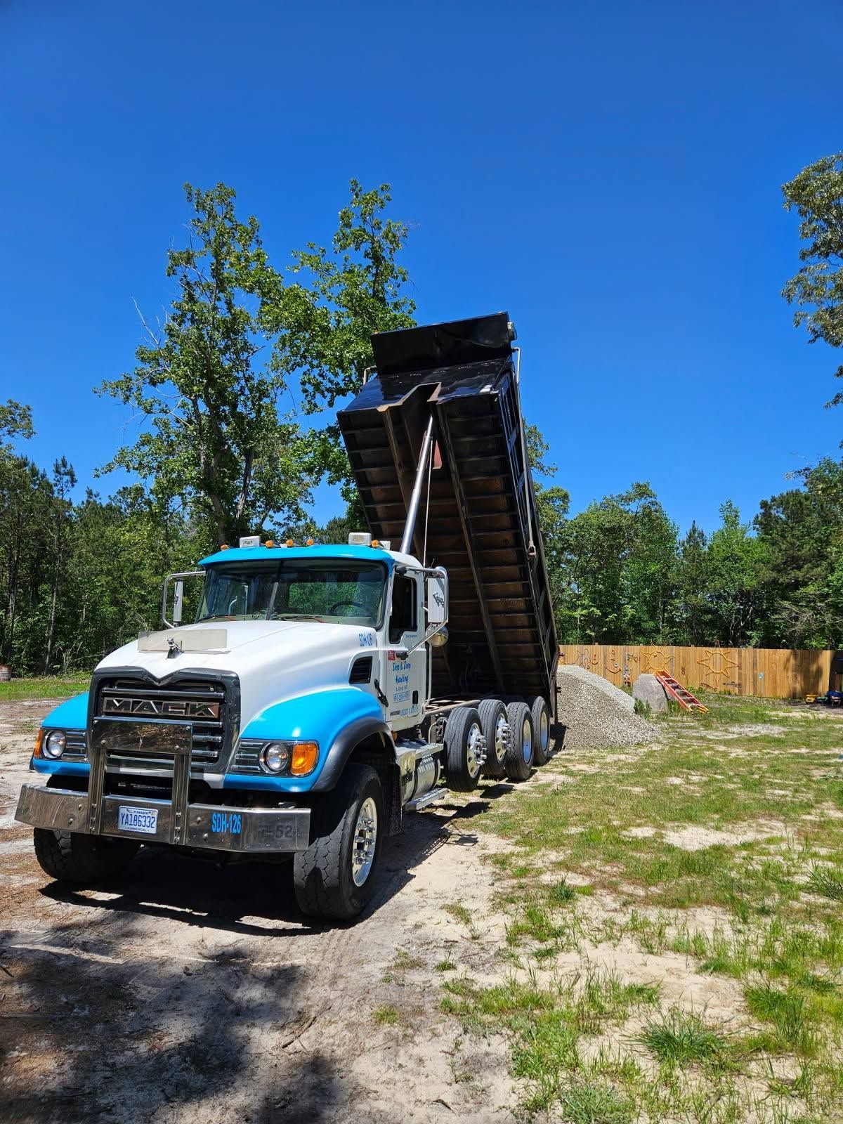 Dump truck with raised bed on a gravel lot under a clear blue sky Dump truck with raised bed on a gravel lot under a clear blue sky