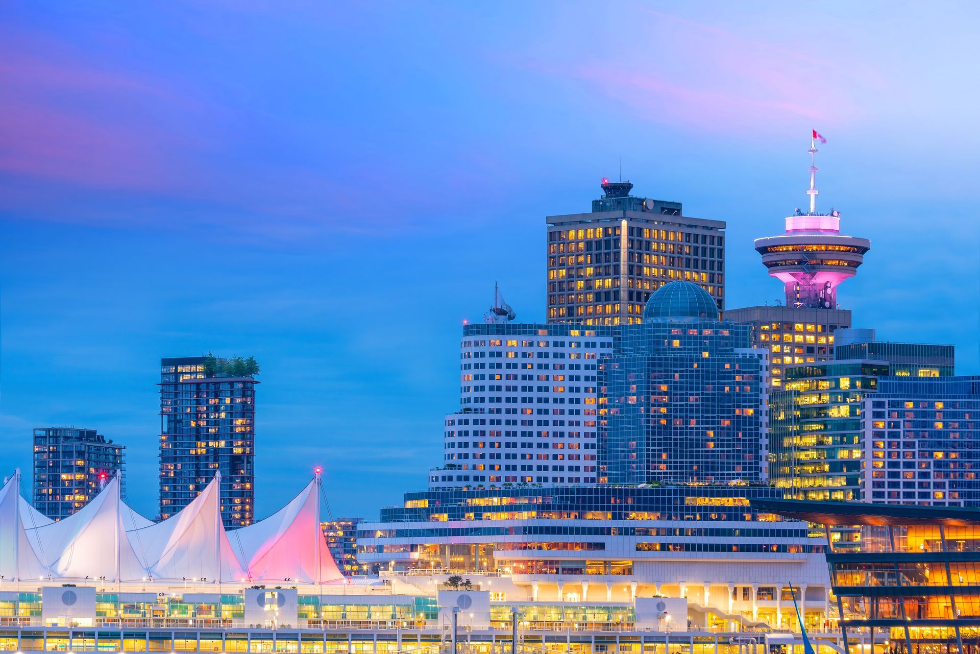 The city skyline of vancouver is lit up at night.