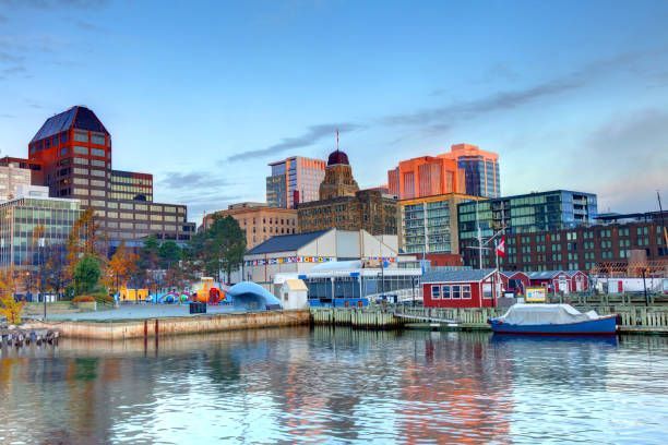 A city skyline is reflected in the water of a harbor.