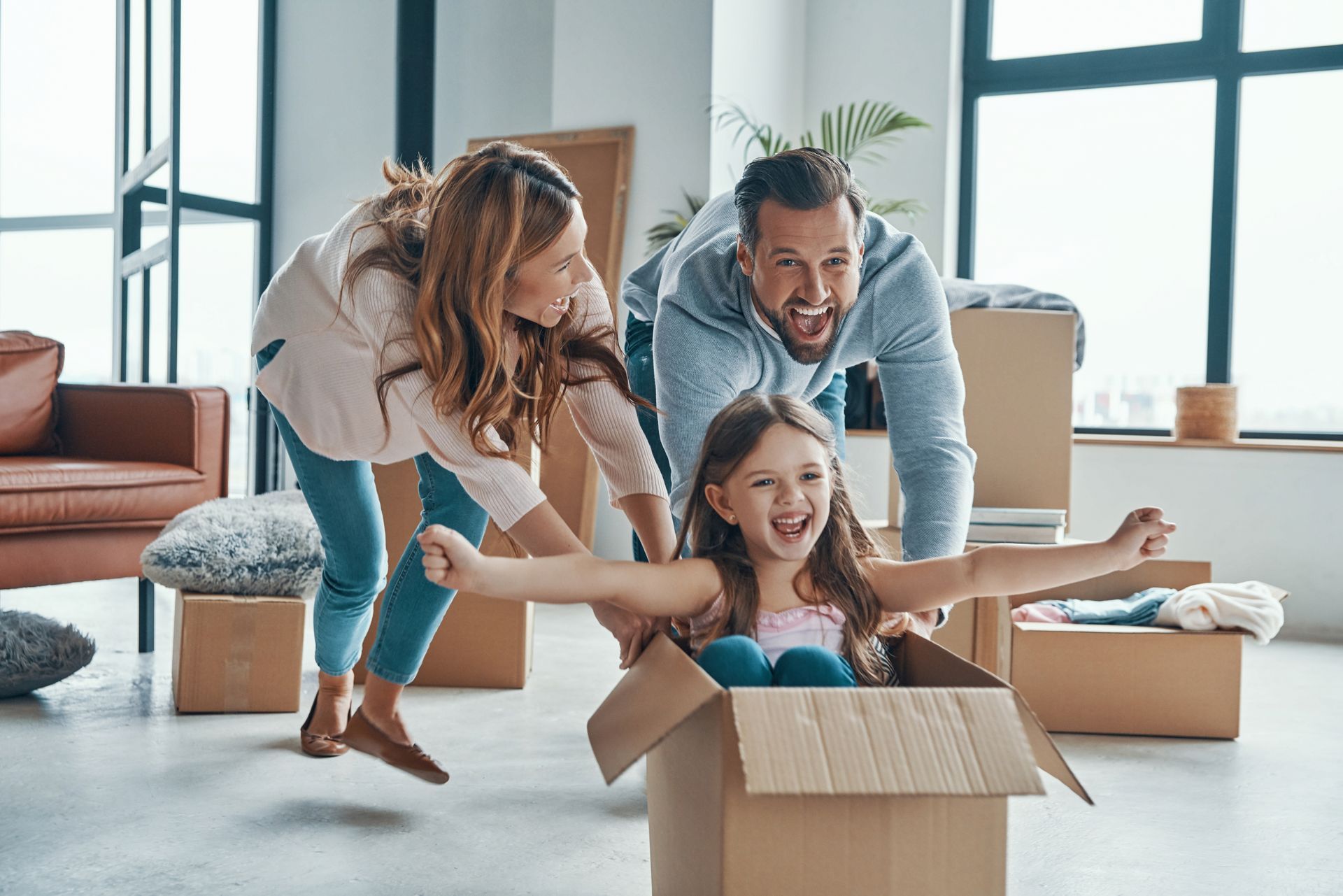 a family is playing with a little girl in a cardboard box .