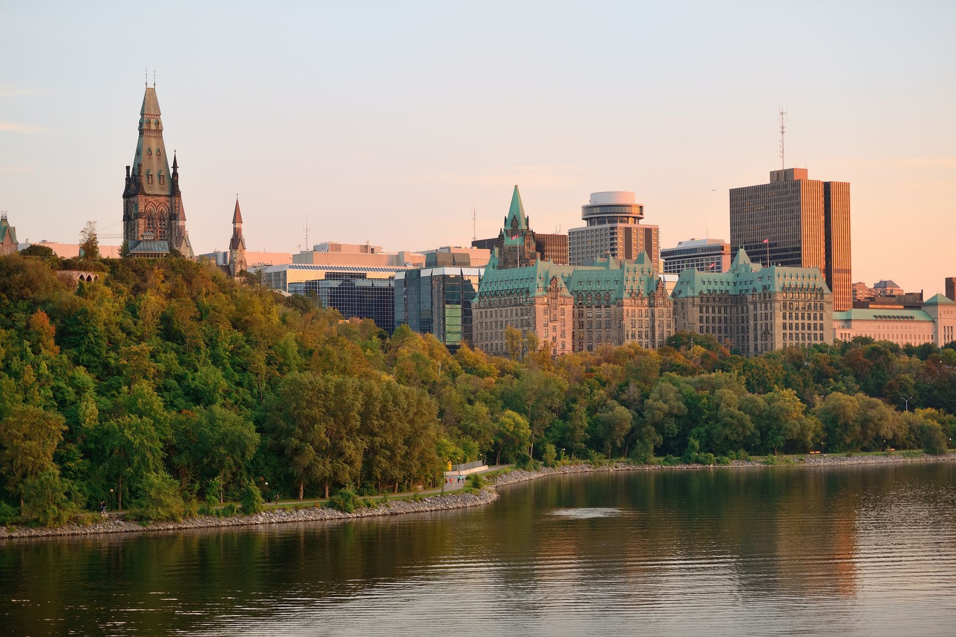 A city skyline with a lake in the foreground and trees in the background.