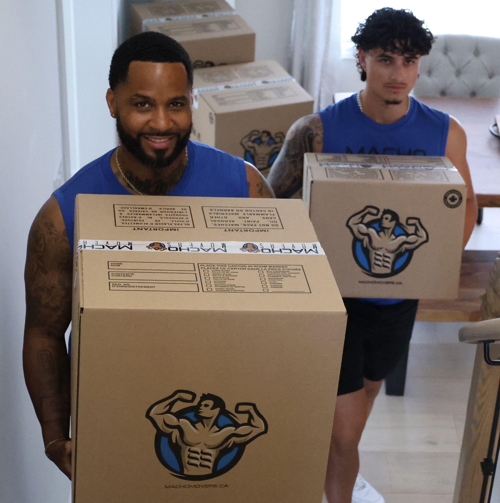 two men are moving boxes in a living room .