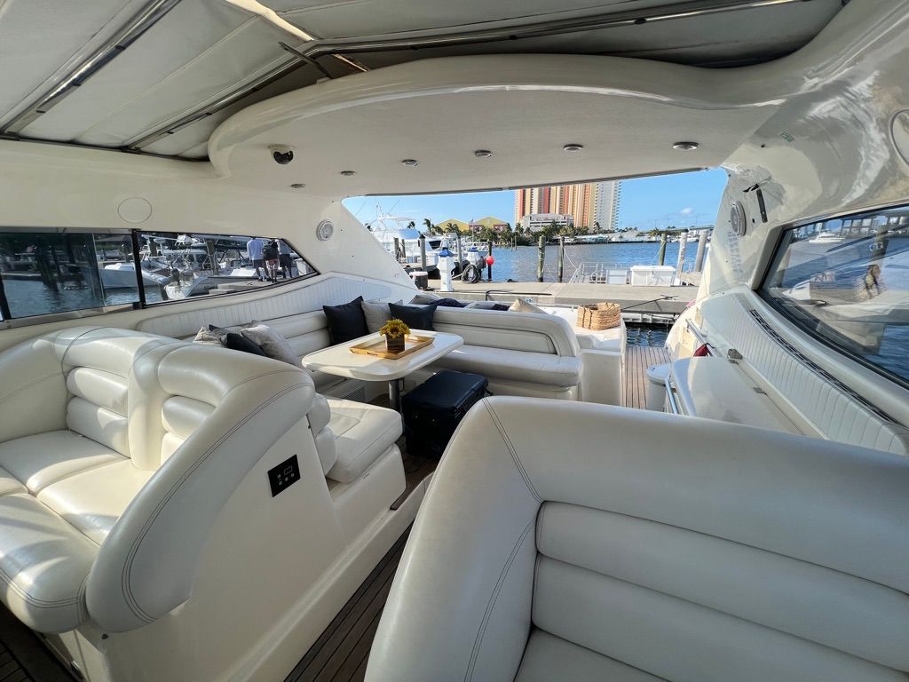 Interior of a white yacht with seating, table, and view of a marina.