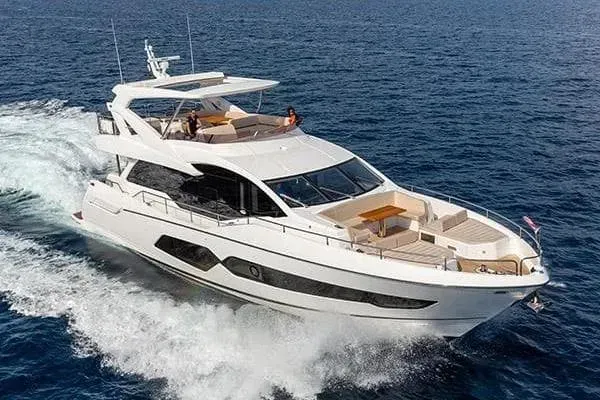 White luxury yacht speeding across open water, leaving a foamy wake