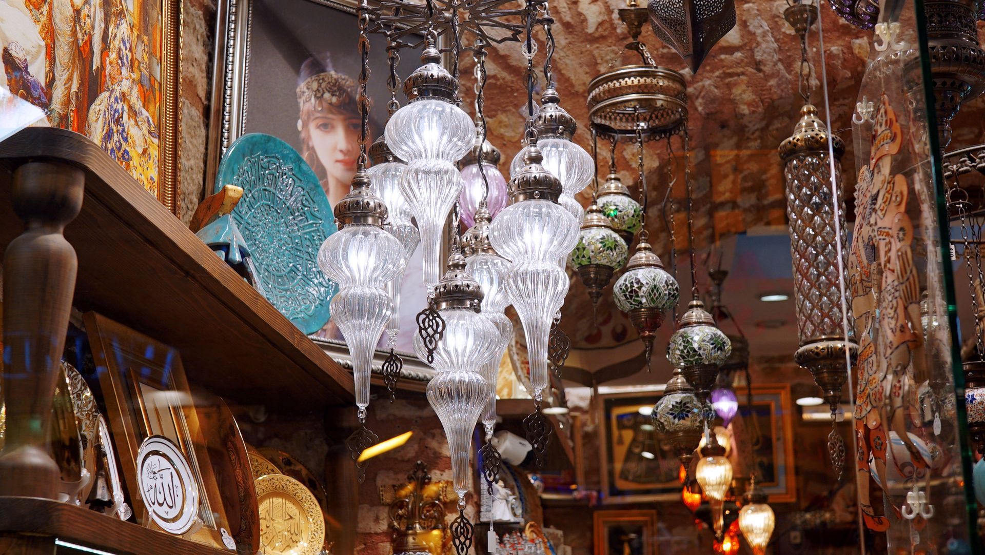 Shop display with ornate glass lamps, shelves of pottery and artwork.