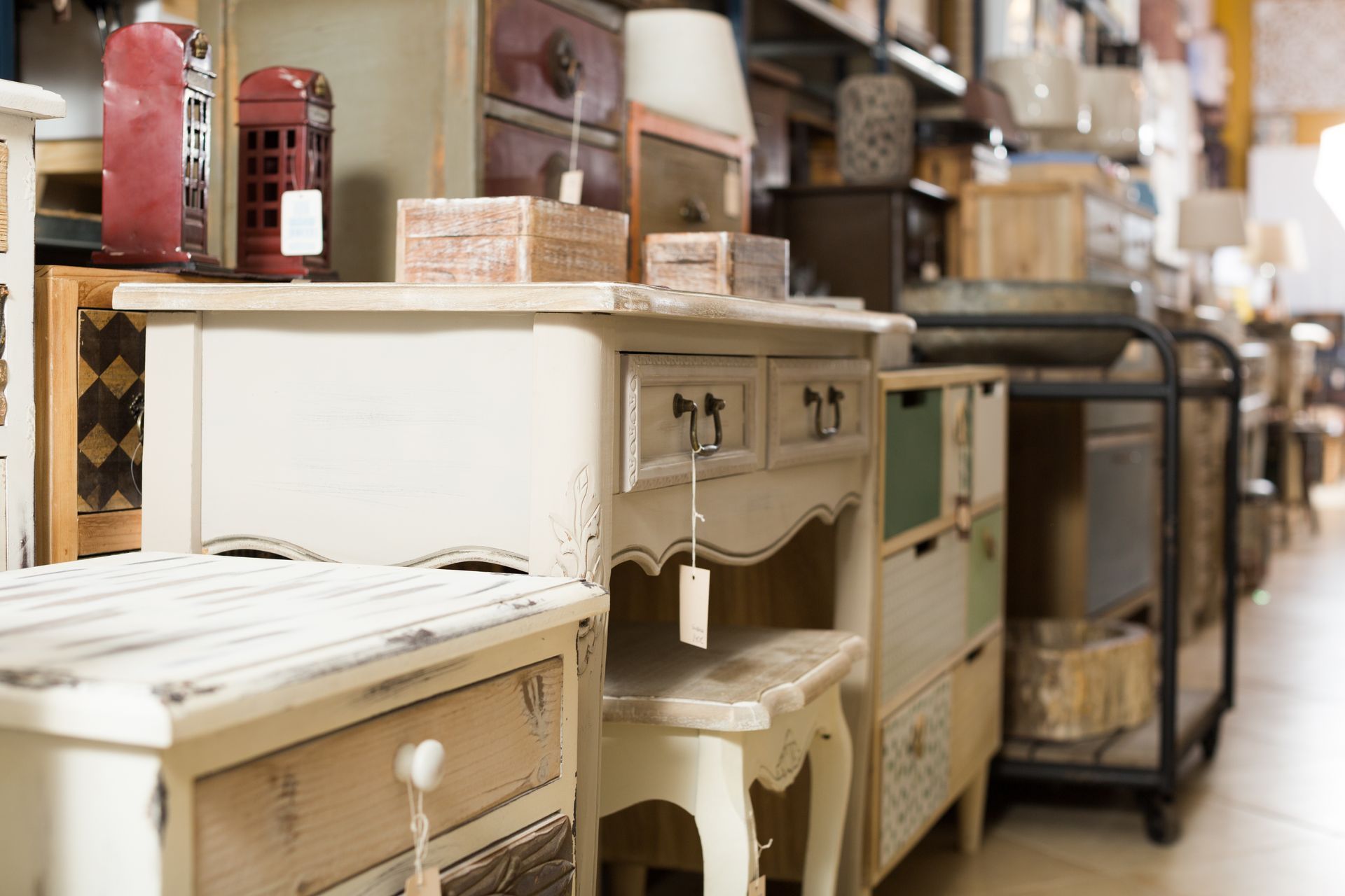 Antique furniture display in a shop, showcasing white, cream, and colorful dressers, tables, and cabinets.