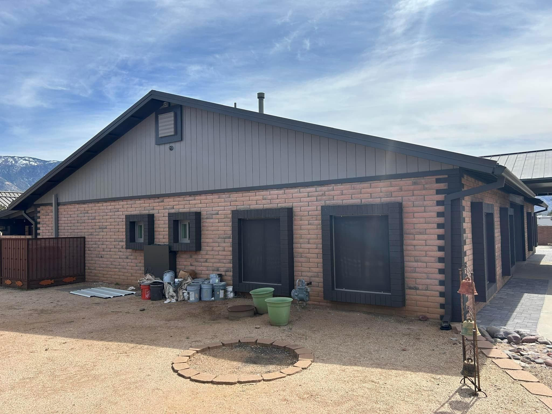 Brick-walled building with brown trim and siding under a blue sky. 