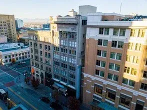 High-angle view of a city street featuring several mid-rise historical and modern buildings bathed in warm sunlight.