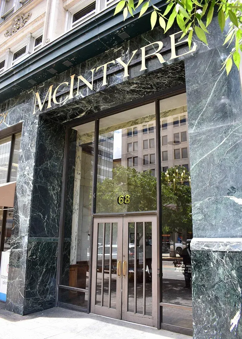 The entrance to the McIntyre Building at 68, featuring dark green marble walls and a glass door.