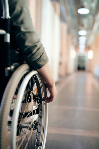 Person in a wheelchair moves down a brightly lit hallway.