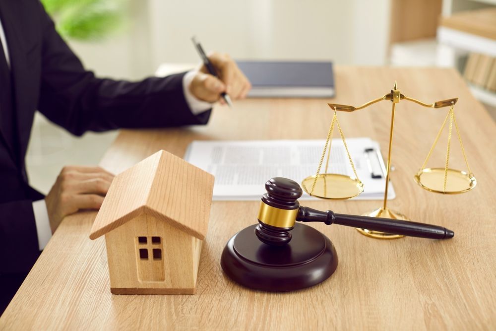 Lawyer’s desk with house model, gavel, and scales of justice during contract review