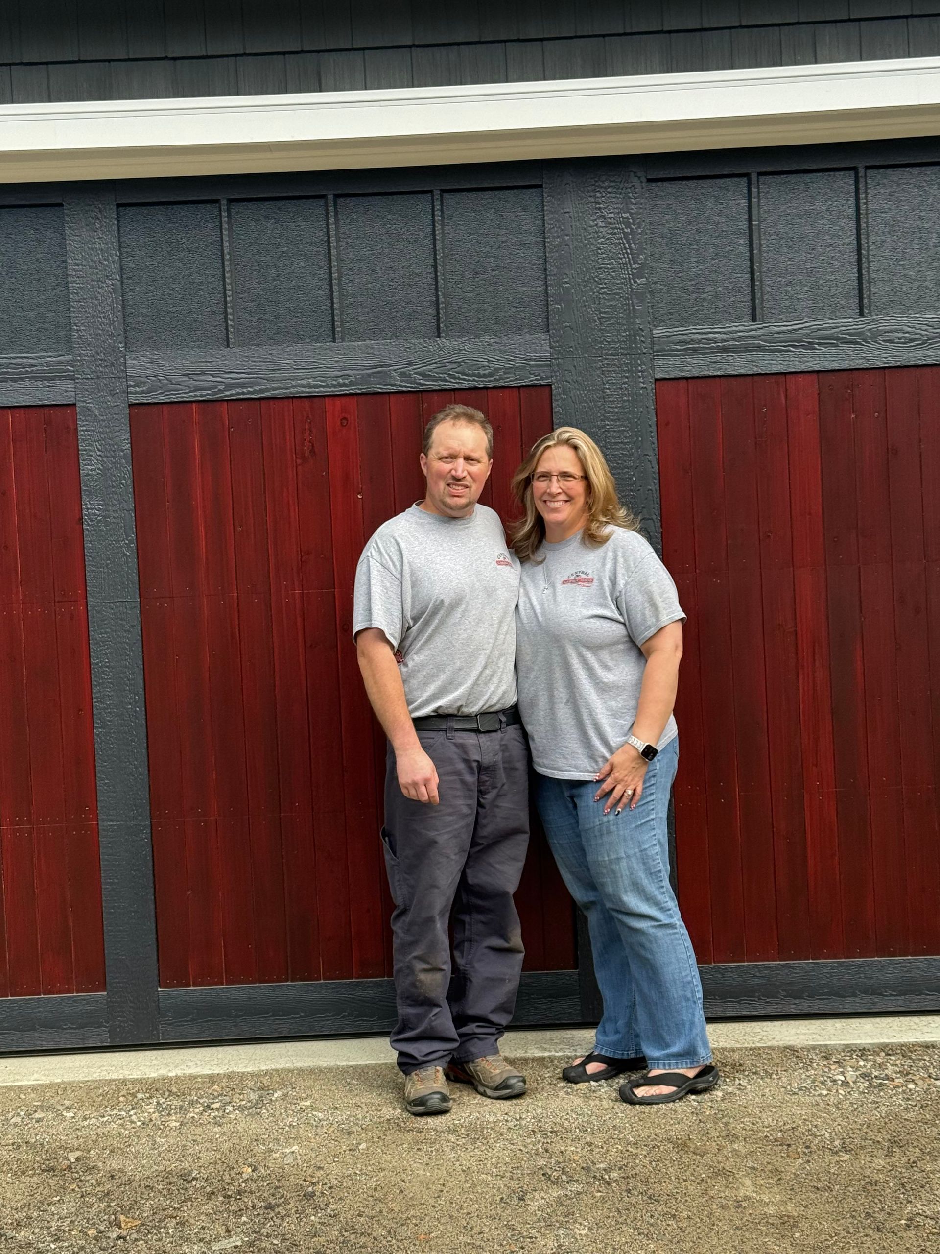 Jeff & Julie Brown in front of a custom garage doors wearing their Central Garage Door Co company gear