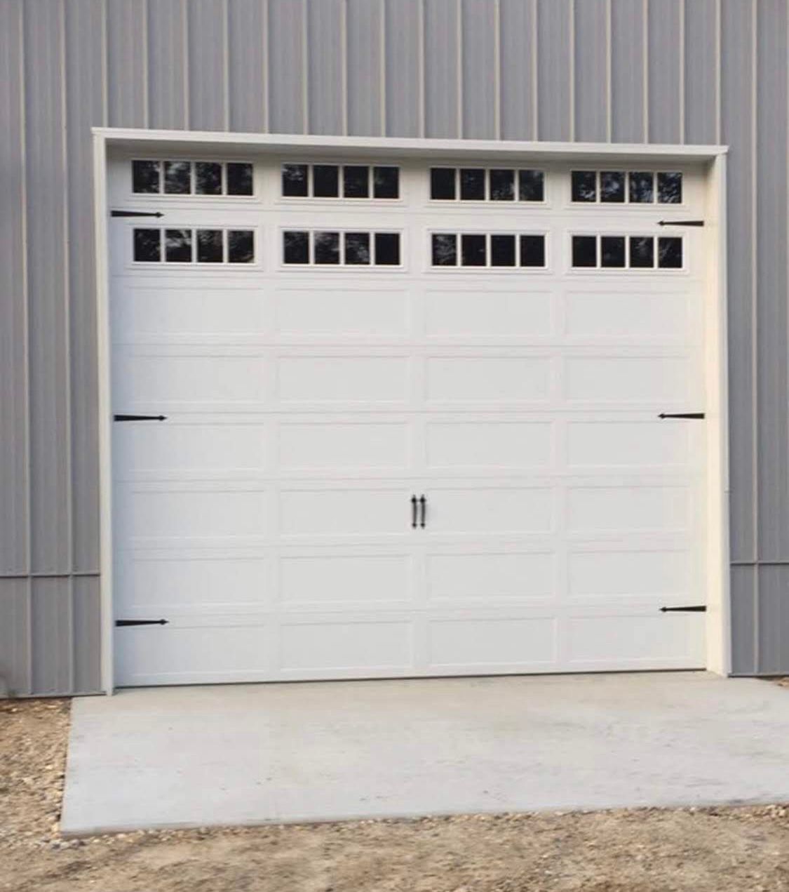 White garage door with rectangular windows above, concrete slab.
