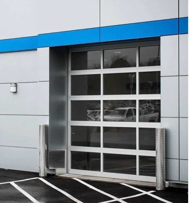 Glass garage door on a modern building, with cars visible inside; white and gray color scheme.