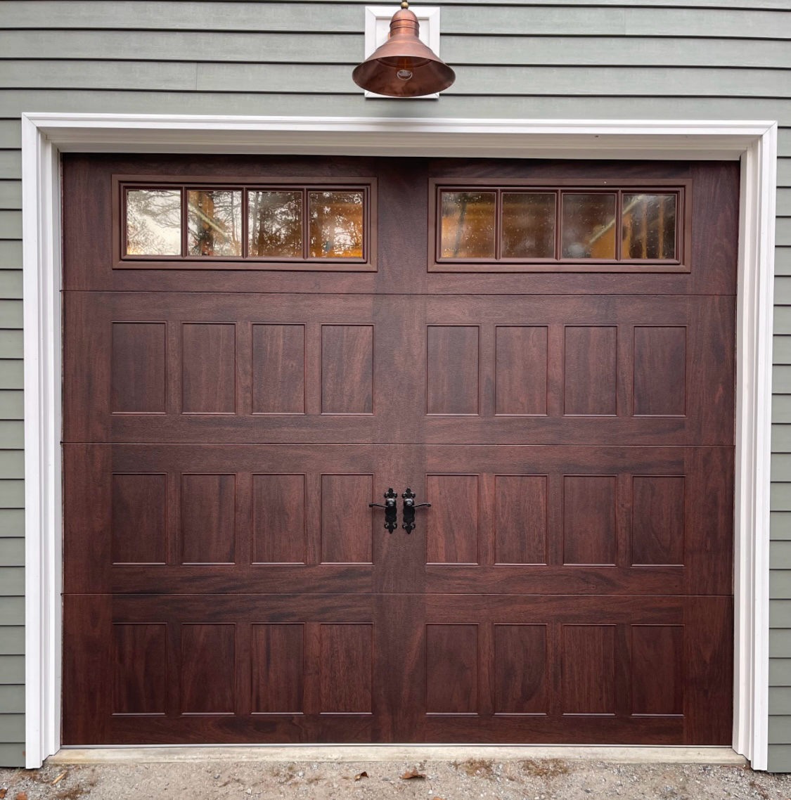 Brown wooden garage door with two window panels above, copper light fixture.