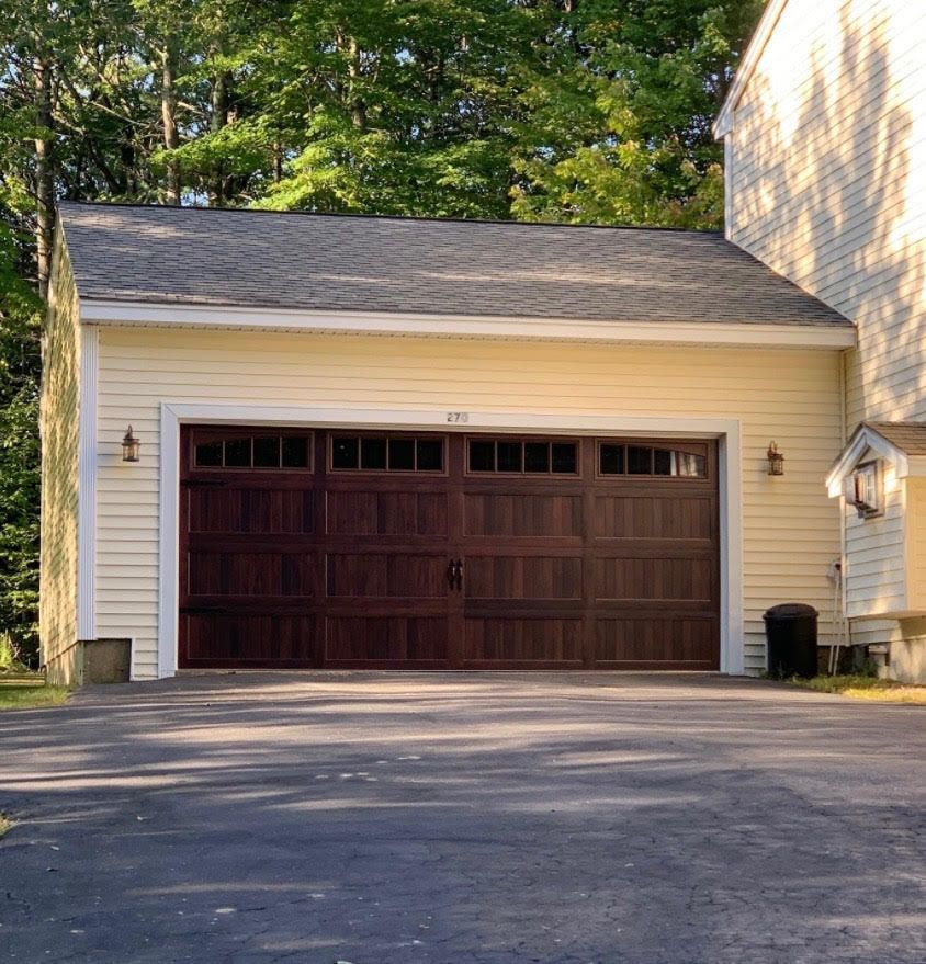Yellow garage with dark brown wooden garage door, asphalt driveway.