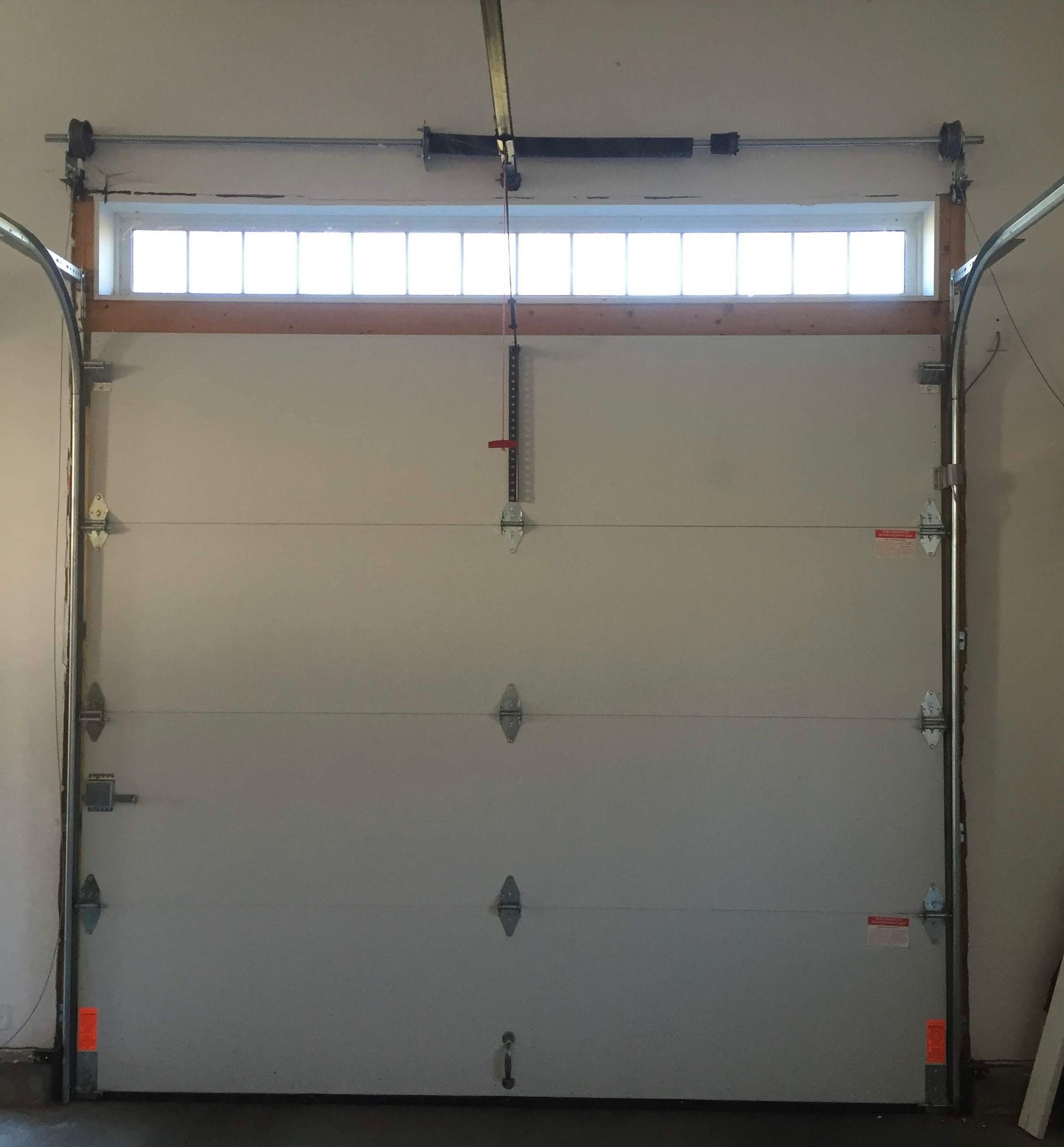 White garage door with window and hardware, inside garage.