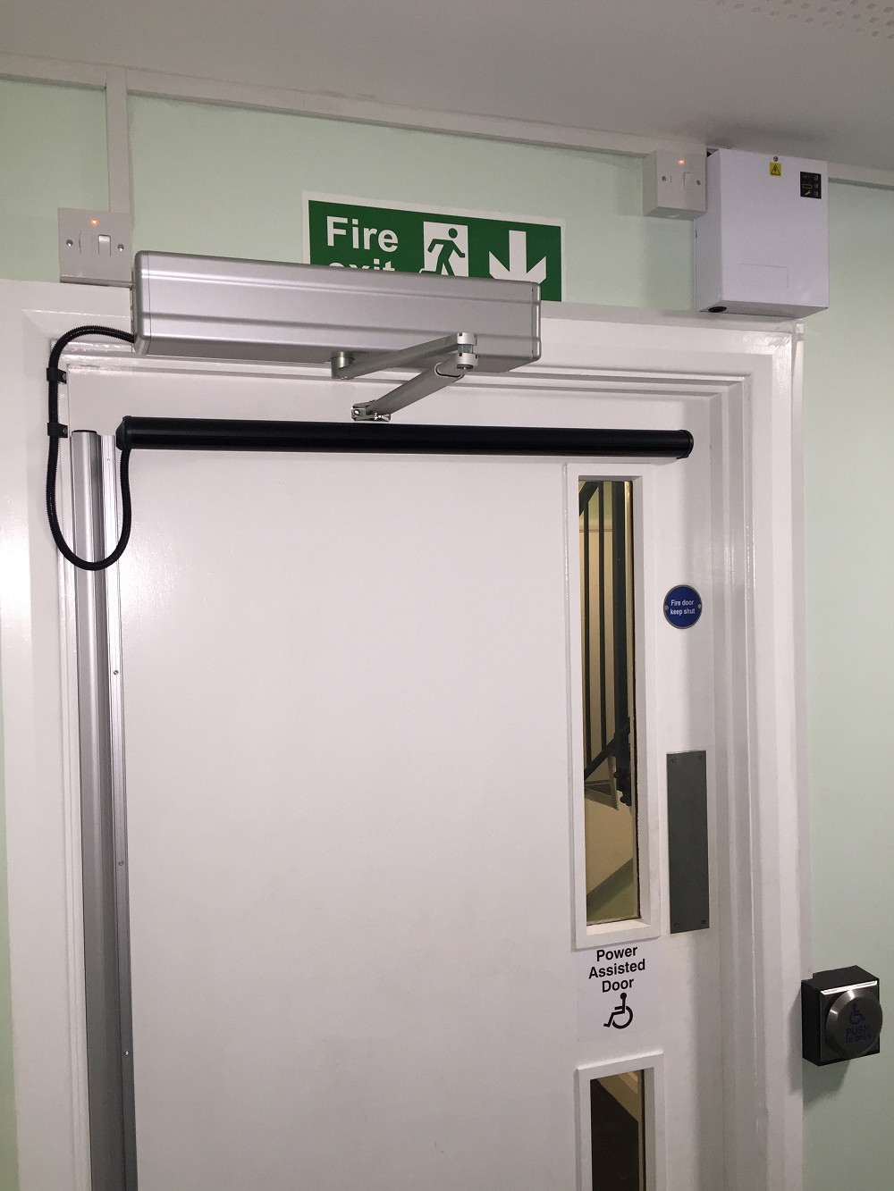 a white door with a green fire exit sign above it