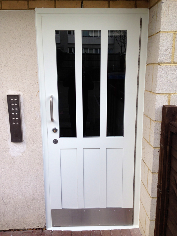 a white door with three windows and a stainless steel trim
