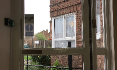 a room with a broken window and a brick building in the background .