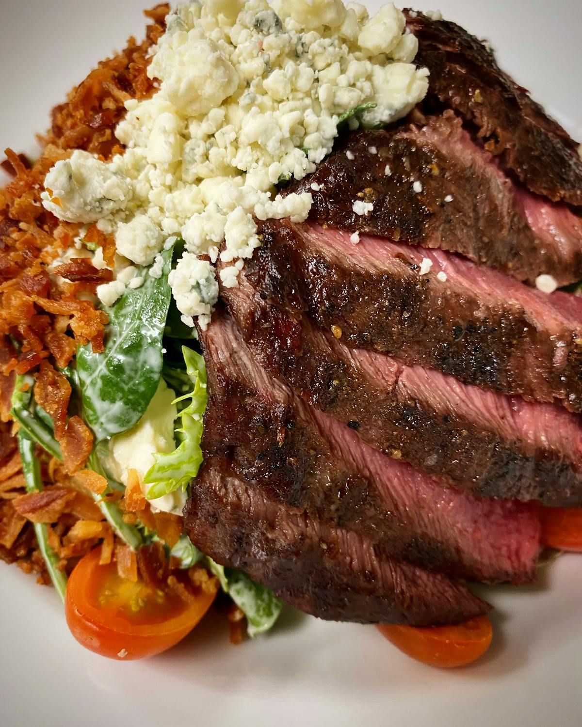 A close up of a plate of food with meat and vegetables on a table.