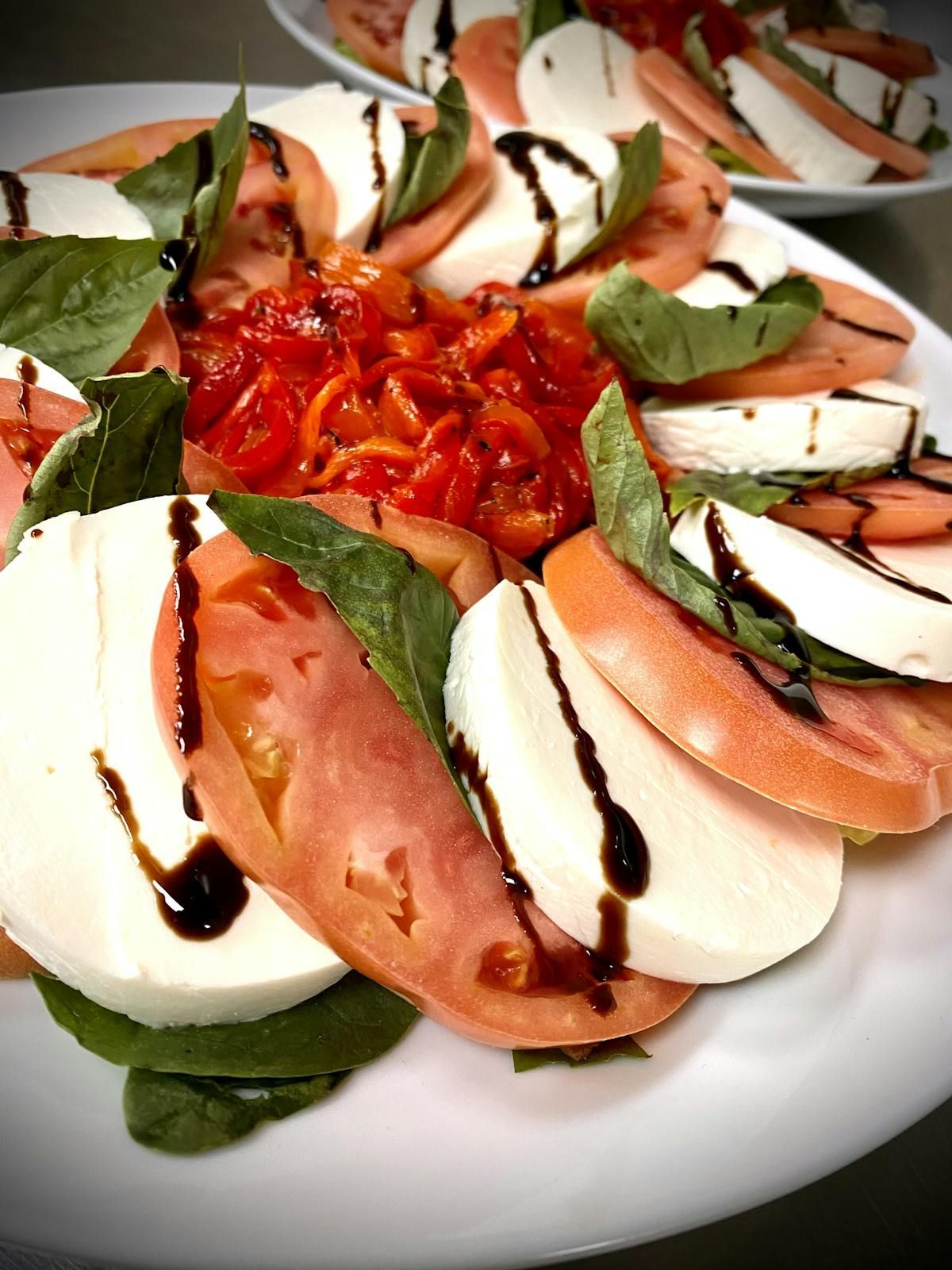 A white plate topped with sliced mozzarella tomatoes and basil