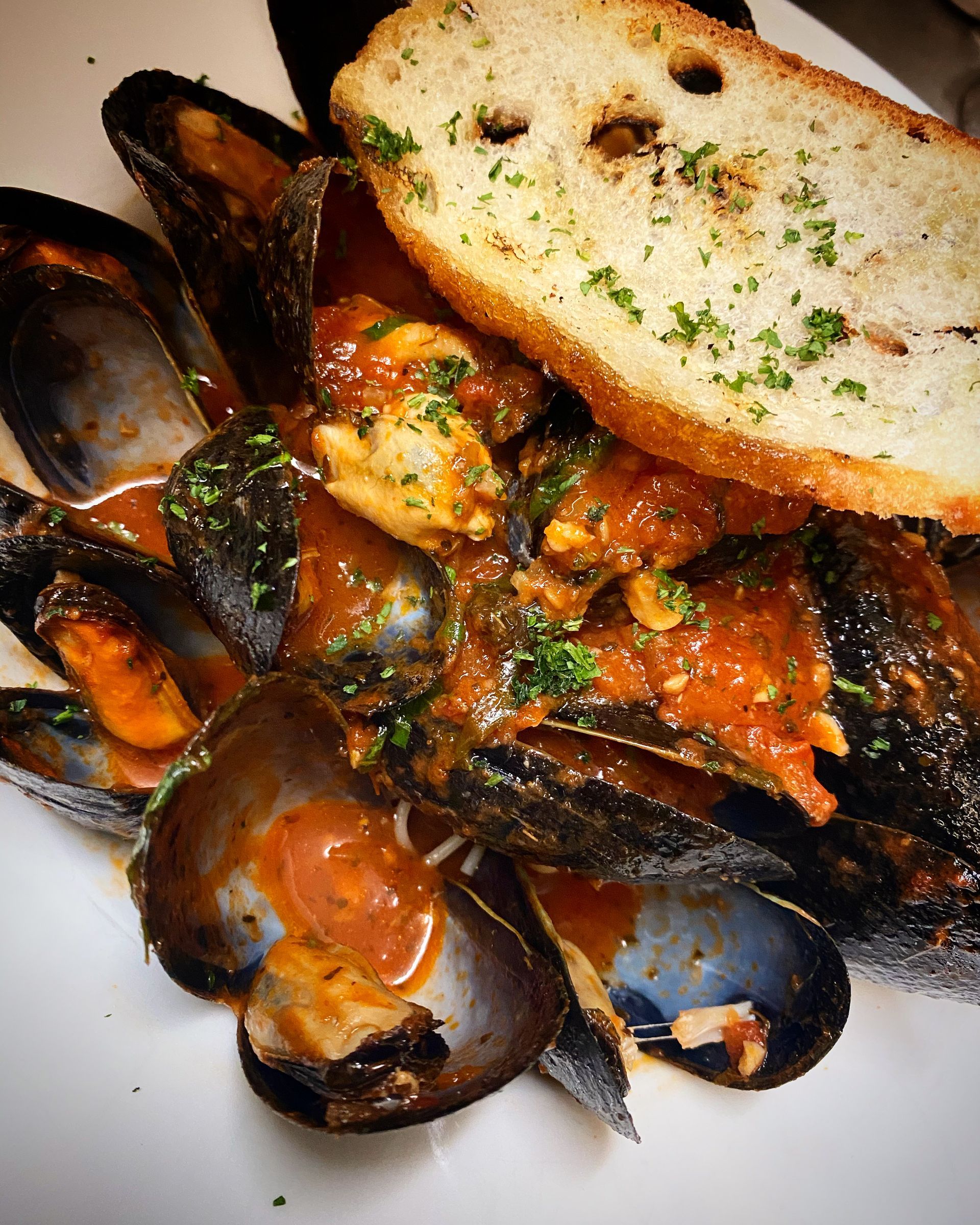 A white plate topped with mussels and garlic bread
