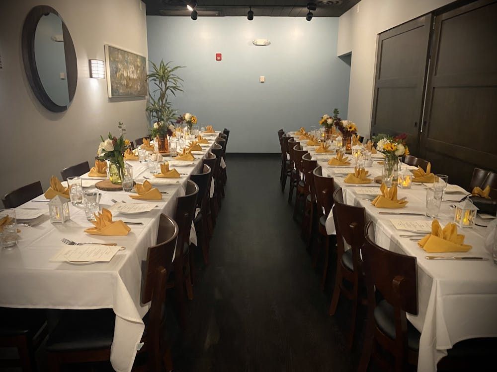 A long table with plates , glasses , and napkins in a room.