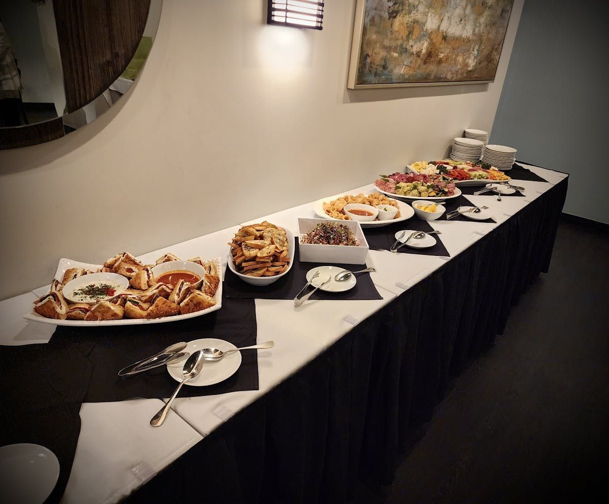 A long table with plates of food and utensils on it.
