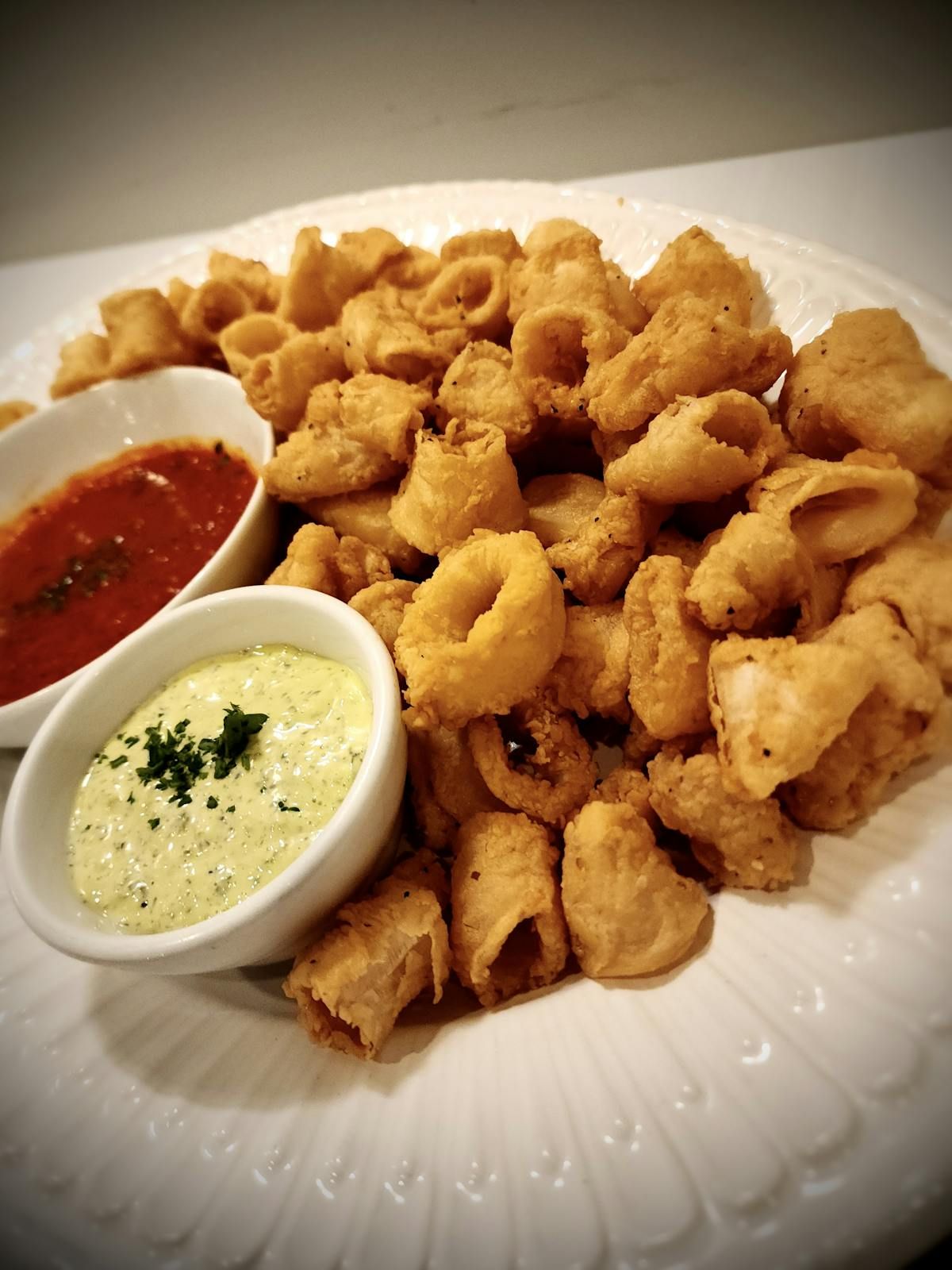A white plate topped with fried calamari and dipping sauces