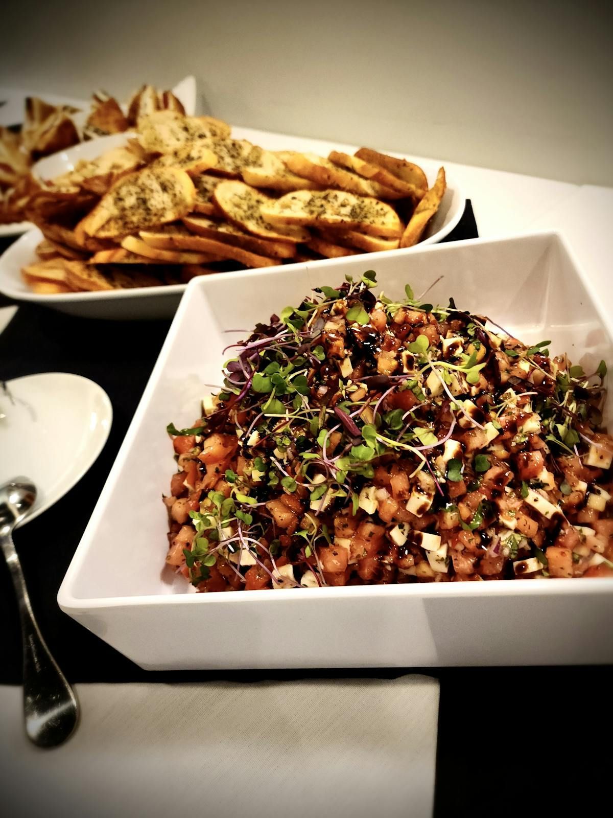 A bowl of salad sits on a table next to a plate of french fries
