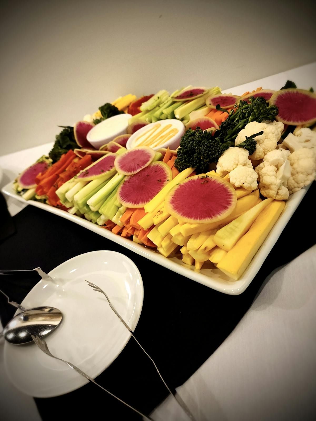 A tray of vegetables on a table next to a plate