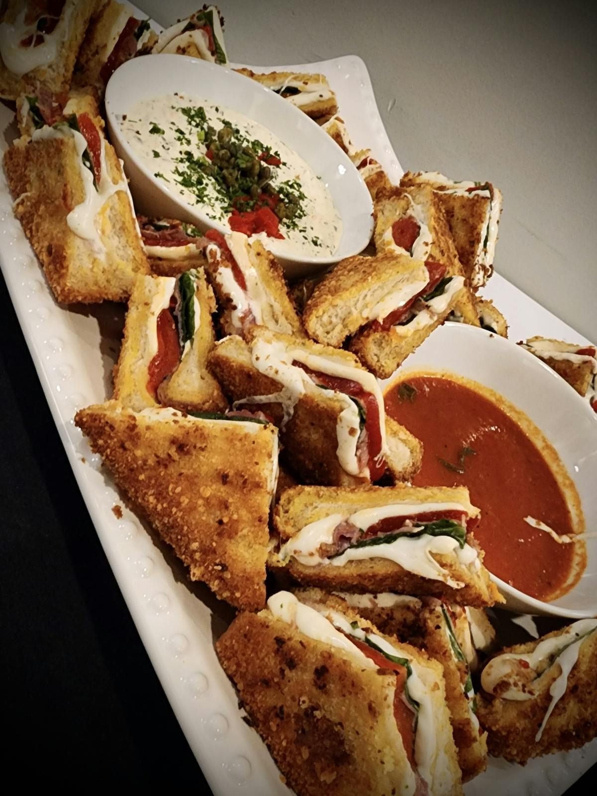 A white plate topped with sandwiches and dipping sauces